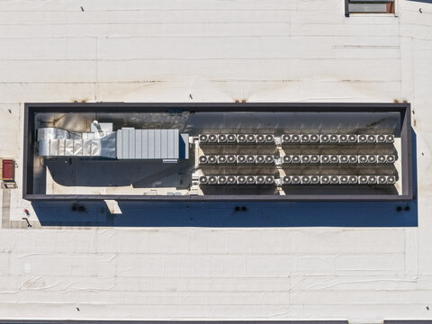 Aerial view of a flat commercial building rooftop featuring a large HVAC system and rows of air conditioning units in Lehi, Utah, United States.