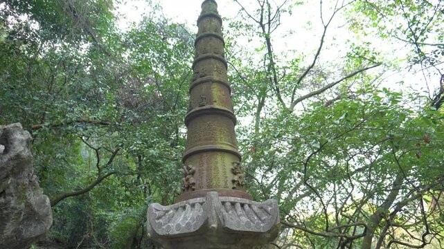 Ancient Carved Stone Pagoda Surrounded by Lush Green Trees