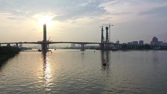 Sunset over river with bridge construction and city skyline