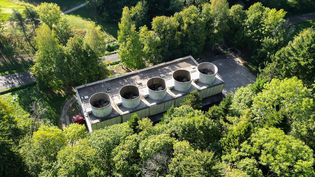 Aerial view of the CERN facility cooling towers surrounded by dense green forest in Echenevex, Auvergne-Rhone-Alpes, France.