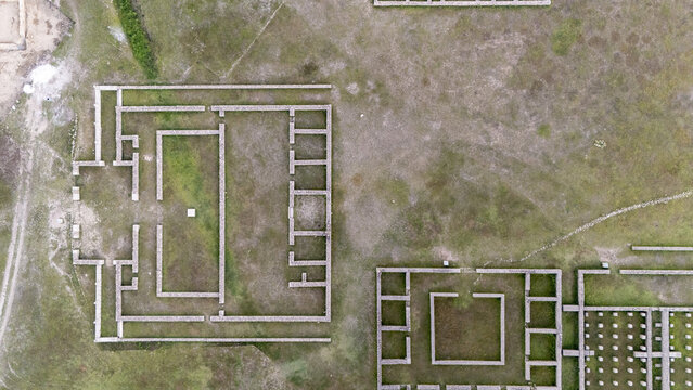 Aerial view of the ancient Roman military camp ruins of Aquis Querquennis with stone foundations and rectangular structures set in a grassy landscape in Porto-Quintela, Ourense, Spain.