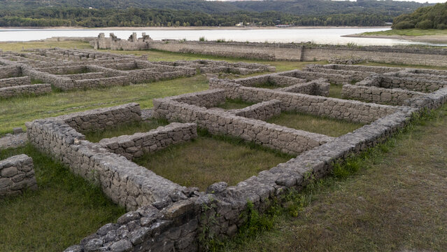 Aerial view of the Roman military camp ruins of Aquis Querquennis with stone foundations and grassy courtyards situated near the reservoir in Porto-Quintela, Ourense, Spain.