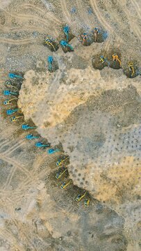 Aerial view of excavators working in an open-pit mine with rocky terrain and dirt paths in Kediri, East Java, Indonesia.