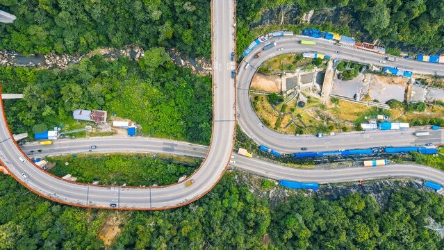 Aerial view of the Kelok 9 bridge, a multi-level overpass winding through the lush green forests of the Harau Valley, Kecamatan Harau, Sumatera Barat, Indonesia.
