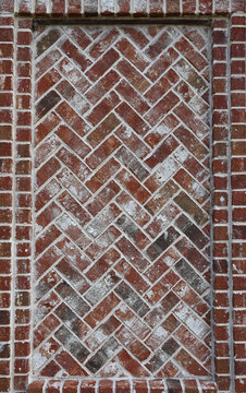 Red and black brick in a recessed herringbone pattern with white mortar, German smear texture, rough, uneven brick faces and a surrounding brick border