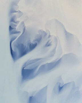 Aerial view of intricate, flowing snow patterns forming wave-like ridges and soft shadows on a frozen landscape in Eyrarbakki, Sveitarfelagid Arborg, Iceland.