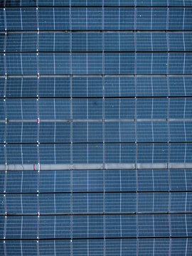 Aerial view of rows of blue solar panels arranged in a grid pattern on a rooftop in Riga, Latvia.
