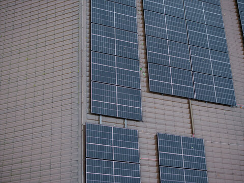 Aerial view of solar panels installed on a brown tiled roof during a rainy day in Riga, Latvia.
