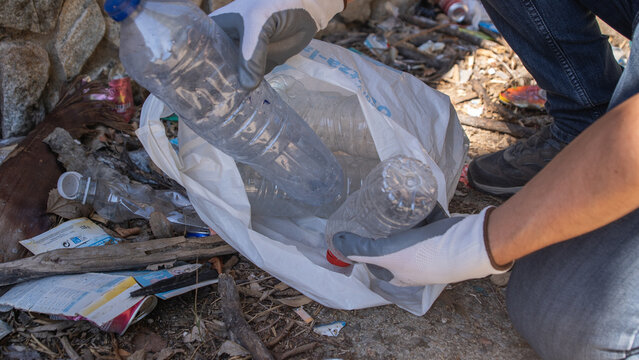 Persona limpiando basura y botellas de pl&aacute;stico en un entorno natural