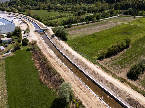 Aerial view of river restoration showing channel widening and flood embankment construction in a rural area.