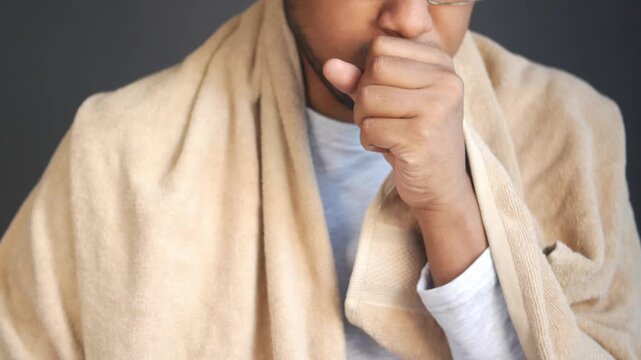Man feeling sick and coughing covered with a blanket, close up shot