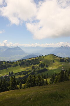 Rolling Alpine meadows with distant mountains under summer clouds