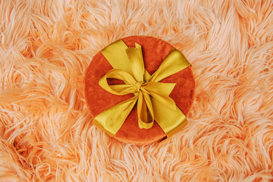 Gift box on pink fur coat, top view, stylish and luxurious holiday