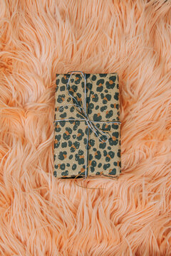 Gift box on pink fur coat, top view, stylish and luxurious holiday