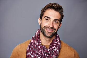 Obraz premium Smile, style and portrait of man in studio with scarf, aesthetic and happy or positive attitude. Confidence, space and person with casual fashion, autumn clothes and cool outfit on gray background