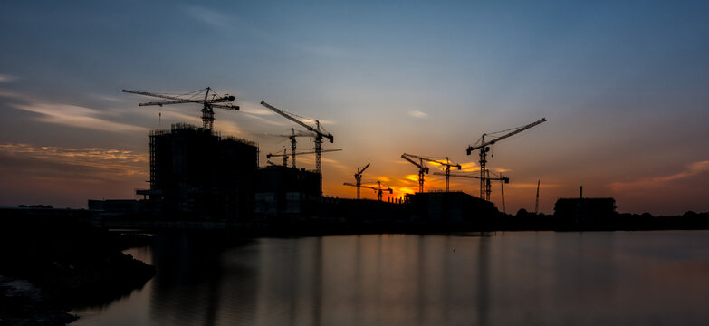 Urban development and building construction site at sunset with water reflection