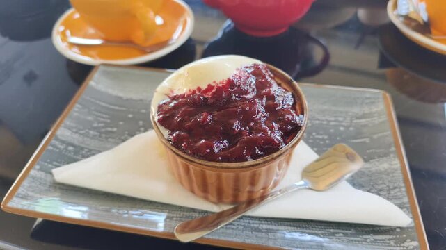 Delicious lava cake served with jam and ice cream on plate during tea time. Cozy cafe table with teapot and colorful cups complements tea time experience with sweet dessert and hot drinks.