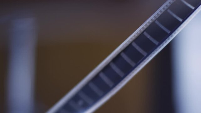 Close up of hands stretching and unrolling a strip of vintage 35 mm negative camera film roll
