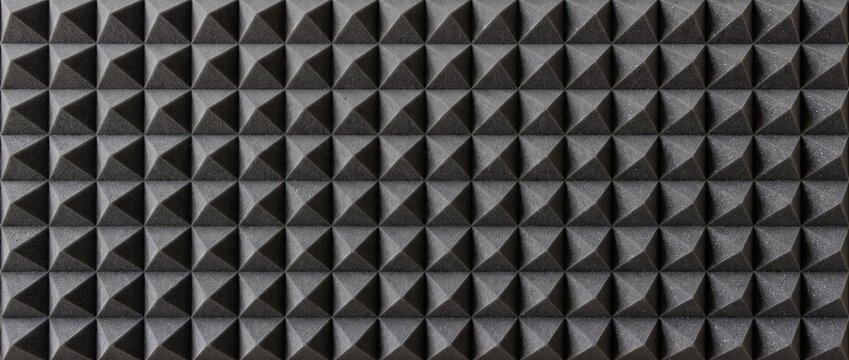 Acoustic foam pyramid panels for soundproofing studio walls. Dark gray wedge absorber treatment surface texture. Soundproof audio recording insulation background