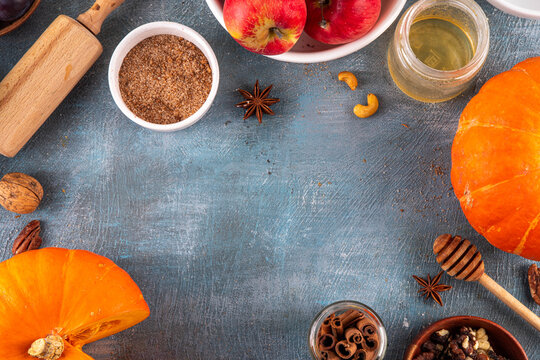 Fall baking, cooking seasonal dessert background with various ingredients - honey, pumpkin squash, brown sugar, cinnamon, spices, red apples, plums, walnuts, pecans. Autumn, thanksgiving bakery backgr