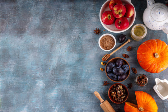 Fall baking, cooking seasonal dessert background with various ingredients - honey, pumpkin squash, brown sugar, cinnamon, spices, red apples, plums, walnuts, pecans. Autumn, thanksgiving bakery backgr