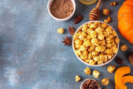 Pumpkin popcorn with caramel and pumpkin spice. Bowl with tasty sweet popcorn covered with pumpkin spice caramel, cinnamon and spices, copy space