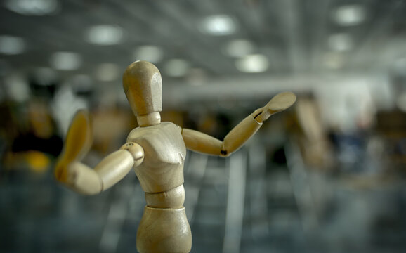 Close-up of a wooden artist mannequin posing with arms raised in a studio