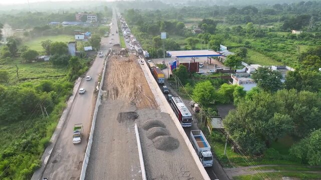 Highway widening roadworks causing severe gridlock, captured in a low aerial tracking shot alongside a huge unpaved earthmoving overpass project.