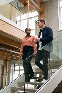 Two coworkers talking while walking down an office staircase