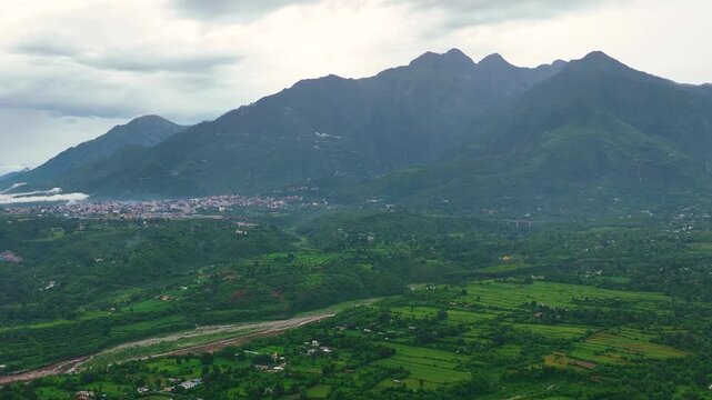 Ascending 4K drone tilt-up showing Mata Vaishno Devi pilgrimage basecamp and misty Himalayan mountain peaks.