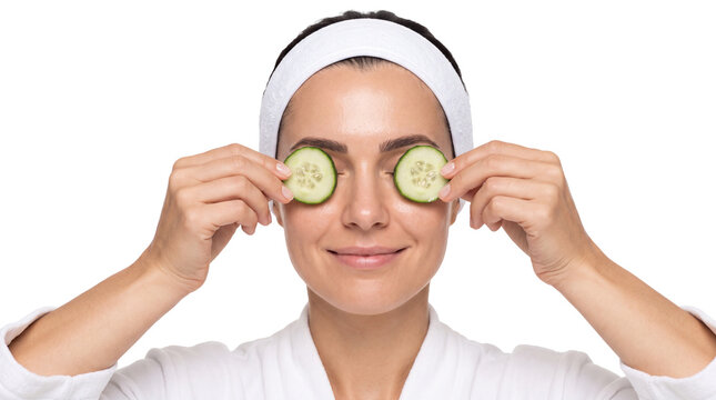 woman holding cucumber slices over her eyes during a spa treatment