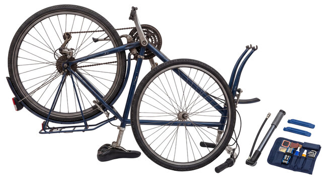 upside down bicycle with repair tools arranged on white background