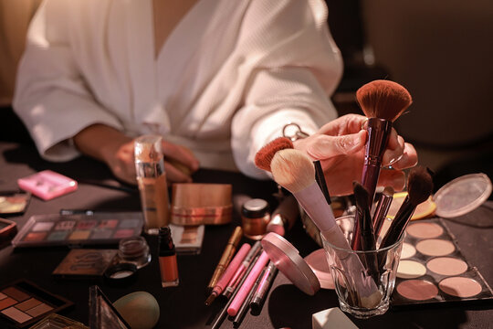 Focused feminine man selects cosmetic tools for an alternative makeup look, meticulously preparing for special occasion, embracing personal beauty