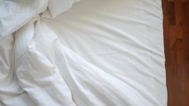 Close up video of white bed sheets and blanket on a bed showing soft fabric and comfortable sleeping area with subtle light and gentle movement
