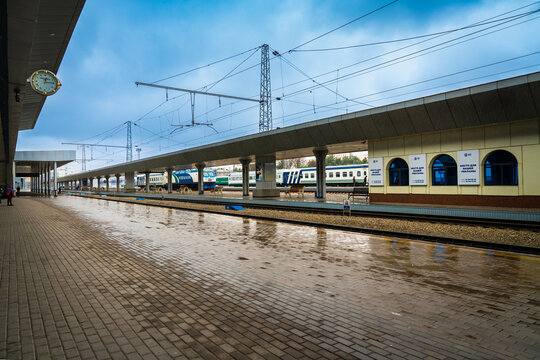 Tashkent, Uzbekistan. 31 December 2025 &ndash; Passenger trains stand on parallel tracks at the Tashkent railway station, viewed from a covered platform after rainfall. Overhead electric wires, platform can