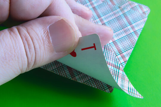 Close-Up Hand Peeking a Playing Card During Poker Game Showing Ace and Sleight of Hand Cheating