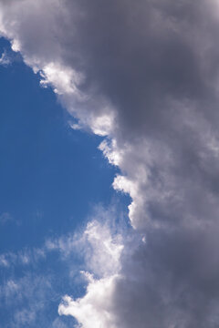 Dramatic Dark Storm Cloud Rolling Over Bright Blue Sky with Light Edges and Contrast