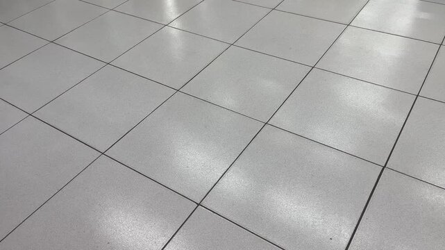 High angle shot of glossy gray ceramic floor tiles with bright reflection