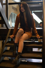 Young Woman Sitting on Industrial Staircase in Urban Interior Setting © AK ST