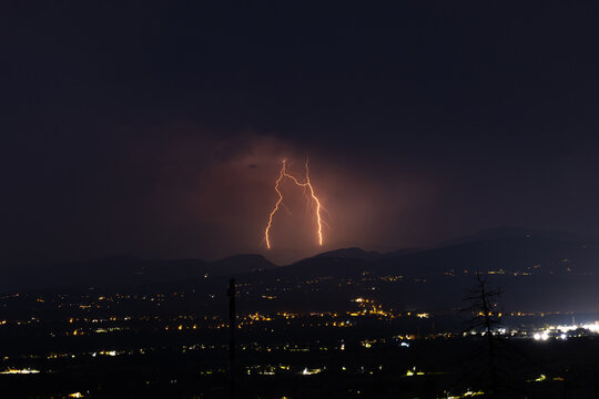 fulmini arancioni sopra un'area collinare tra Italia e Slovenia, durante un temporale notturno estivo, scienza e meteorologia