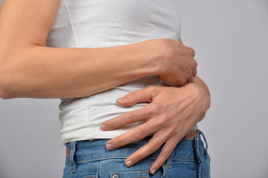 Frau h&auml;lt sich den Unterbauch mit beiden H&auml;nden. Symbol f&uuml;r Bauchschmerzen, Verdauungsbeschwerden, Menstruation, Kr&auml;mpfe, Unwohlsein, Gesundheit und medizinische Beschwerden.