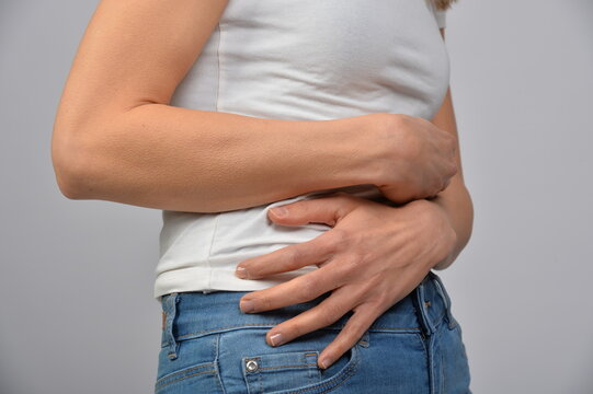 Frau h&auml;lt sich den Unterbauch mit beiden H&auml;nden. Symbol f&uuml;r Bauchschmerzen, Verdauungsbeschwerden, Menstruation, Kr&auml;mpfe, Unwohlsein, Gesundheit und medizinische Beschwerden.