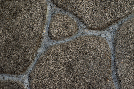Dark stone wall texture background with irregular natural river rocks. Rustic black cobble stone cladding wall pattern background for architecture design