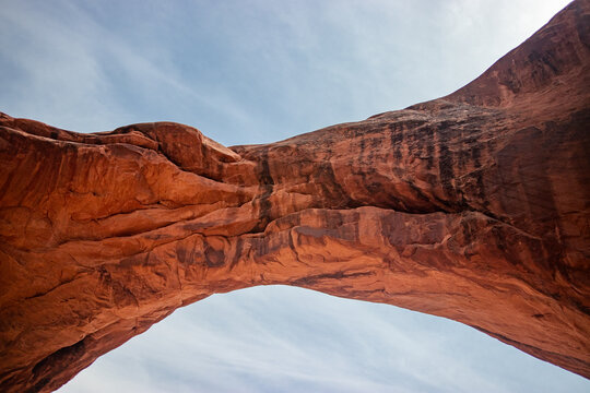View of Arches National Park featuring a massive natural sandstone arch against a clear blue sky in Grand County, Utah, United States.
