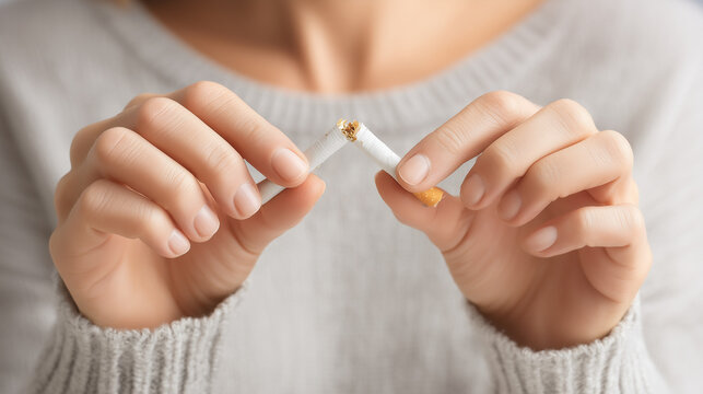 Close-up of hands breaking a cigarette in half, symbolizing smoking cessation, quitting tobacco, addiction recovery and a healthy lifestyle choice.