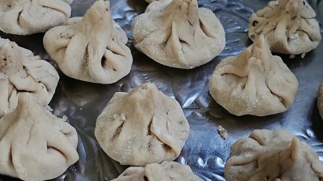 Ukdiche modak hand-shaped dumplings arranged on a traditional silver platter before steaming, showcasing authentic Maharashtrian culinary heritage and festive sweet preparation.