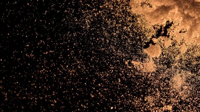 Close up of snow patterns on a glass surface, creating a sparkling effect against the darkness.