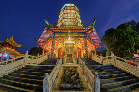 View of the illuminated Pagoda Avalokitesvara at night, featuring ornate architectural details, stone staircases, and a deep blue twilight sky in Banyumanik, Central Java, Indonesia.