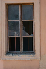 Fototapeta premium old broken window wooden frame cracked glass metal bars abandoned building beige wall weathered texture concept of urban decay, history, architecture