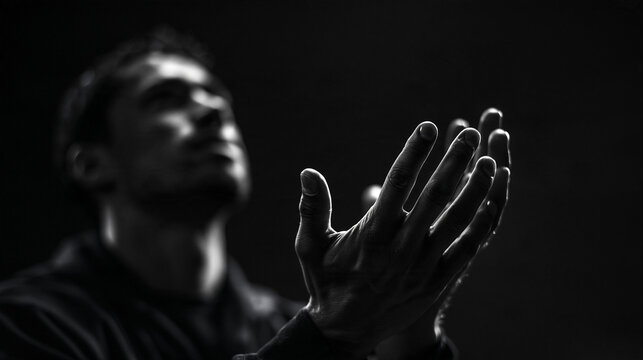 Man Praying with Raised Hands in Dark